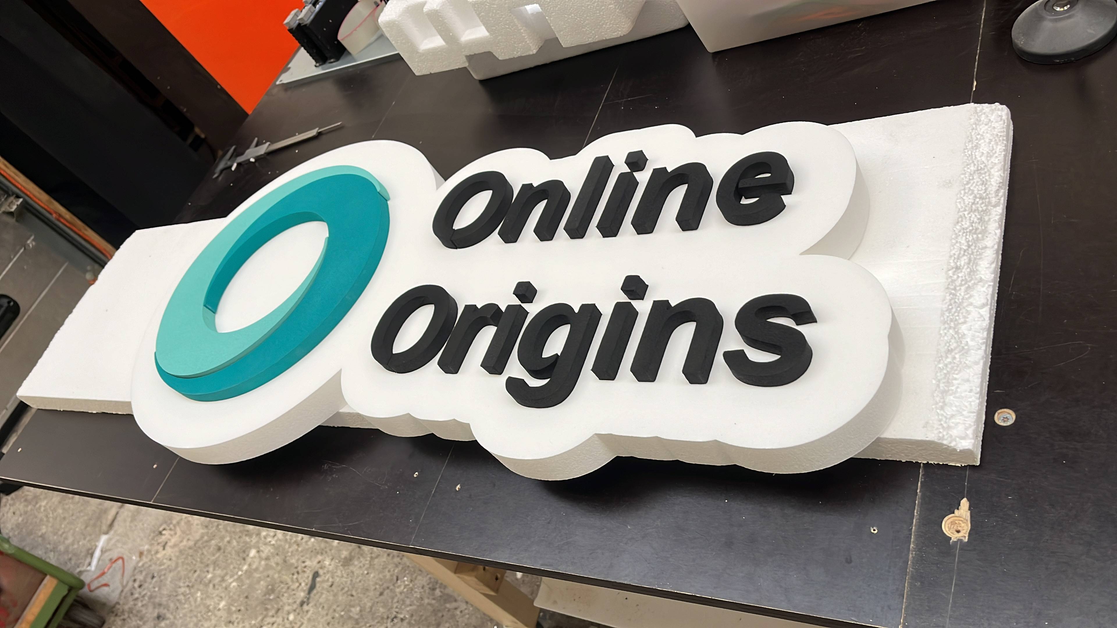 3D sign with 'Online Origins' branding on a black surface