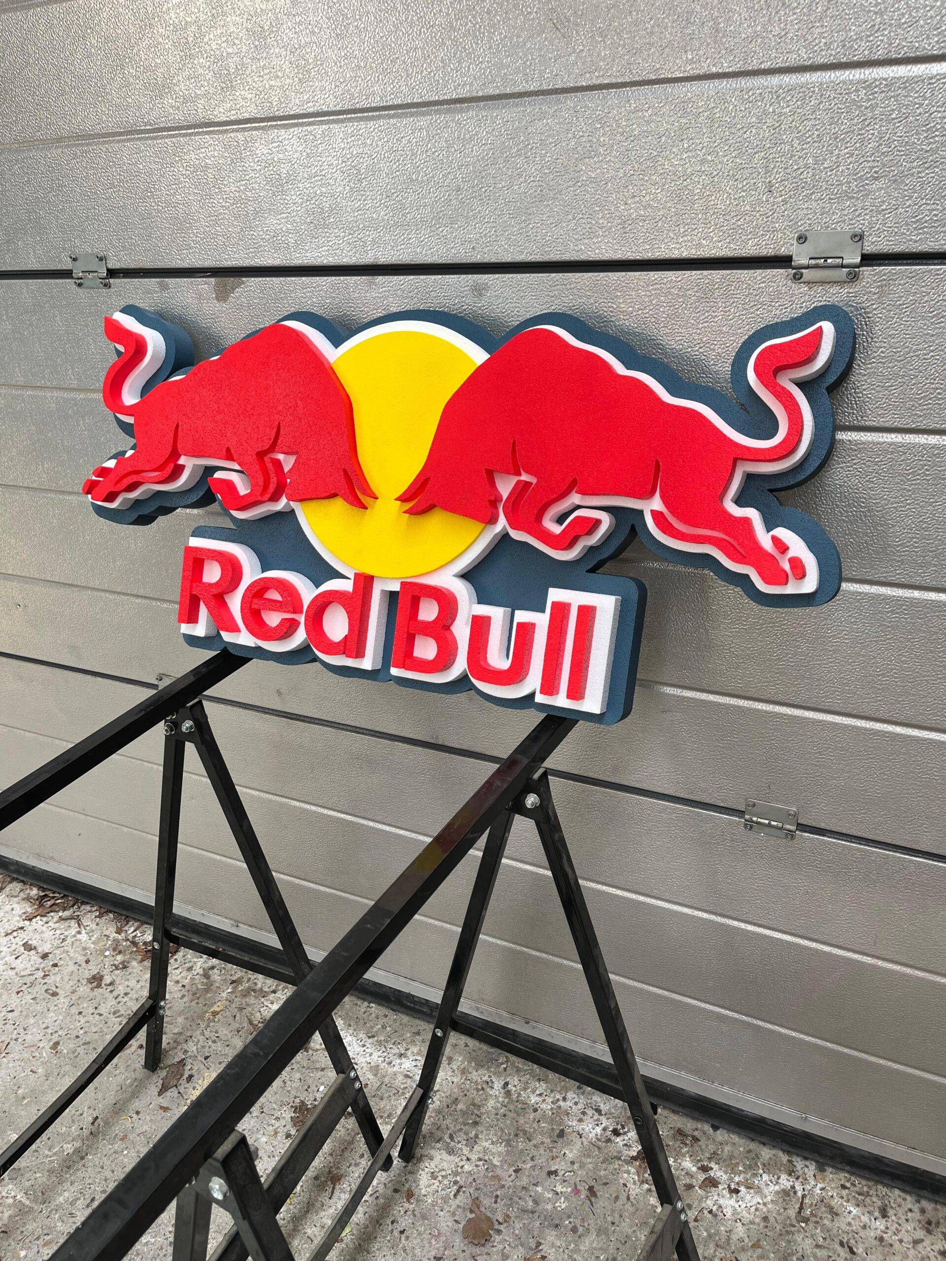 Red Bull logo on a stand against a gray wall